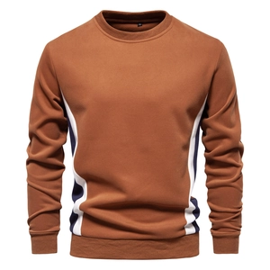 Detail of crewneck sweatshirt showing tri-color splicing and ribbed cuffs in caramel brown