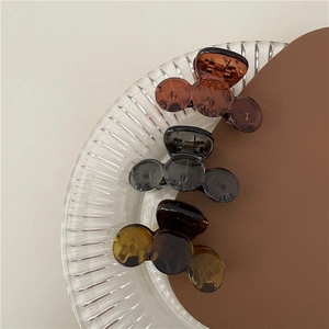 Detailed close-up of brown, amber, and grey mini hair claws on a textured glass tray