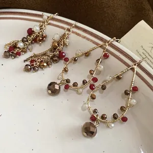 Vintage crystal fringe drop earrings and beaded hoops on a ceramic plate
