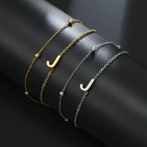 Detailed shot of gold and silver initial J bead bracelets on a black display stand
