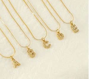 Detail of gold-plated stainless steel letter pendants A-E with crystal inlay on chains