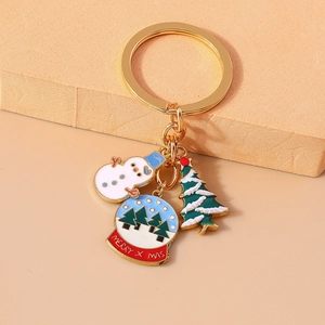 Christmas snowman and crystal ball metal keychain with tree pendant on beige background
