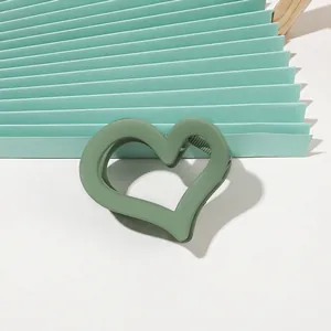 Detail shot of heart-shaped green matte hair claw clip with internal anti-slip teeth