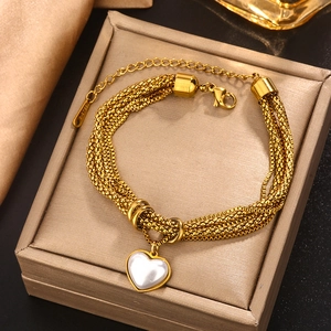 Double-layered gold twisted chain bracelet with heart-shaped shell pendant on jewelry box