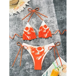Two-piece halter bikini set featuring orange gradient skull print and side-tie bottoms