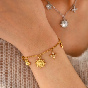 Gros plan de charms soleil et fleur dorés avec cristaux sur un bracelet de style bohème