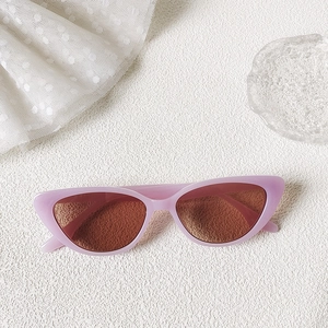 Detailed close-up of retro cat-eye sunglasses with pale pink frames and brown lenses