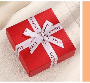 Close-up of a red jewelry gift box featuring a white ribbon with Crystal Jewelry text