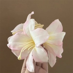 Close-up of a pink and white gradient lily flower hair claw clip with realistic fabric petals