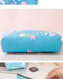 Detail view of floral blue waterproof PU makeup bag with zipper and textile texture