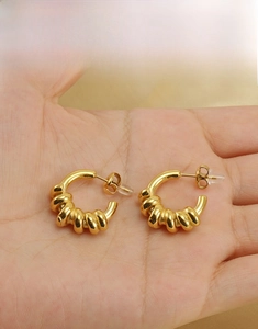 Détail de boucles d'oreilles créoles torsadées en or 18 carats sur fond de soie