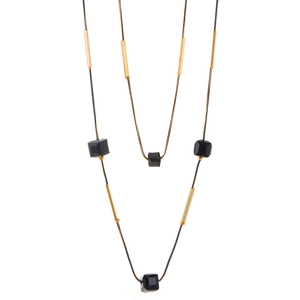 Detalle de un collar largo de doble capa minimalista con cordón negro y tubos dorados