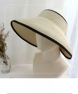Detail of beige straw visor with black ribbon trim and wide brim for sun protection