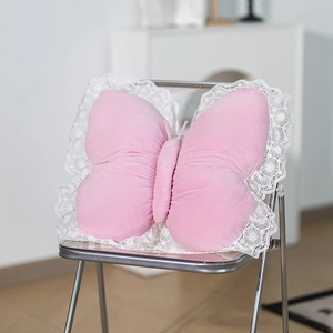Pink plush butterfly decorative pillow with white lace trim on a silver chair