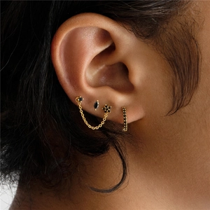 Close-up of gold-plated silver earring set featuring black gems and chain links