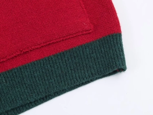 Close-up of red knitted cardigan with dark green ribbed cuffs and textile texture
