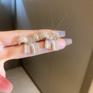Macro shot of sparkling bow stud earrings with clear cubic zirconia in gold setting