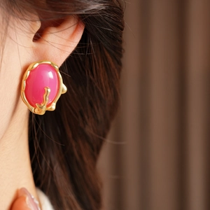 Détail de la boucle d'oreille vintage dorée avec résine rose sur l'oreille du mannequin