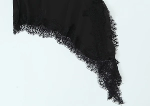Detailed close-up of delicate black lace trim on elegant satin fabric of the dress