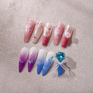 Detail of pink and purple gradient press-on nails with 3D heart gems and ribbon bows