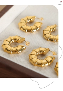 Detailed macro view of 18k gold-plated C-shaped bamboo texture earrings in a display box