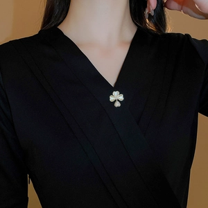 Detail of flower brooch with cat-eye petals and cubic zirconia pendant on black fabric
