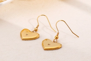 Macro detail of golden heart hook earrings with mirror finish and sparkling zircon