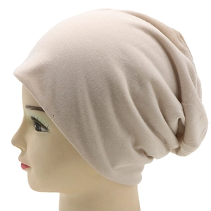 Detailed side view of beige knitted slouchy beanie on a head form with soft texture