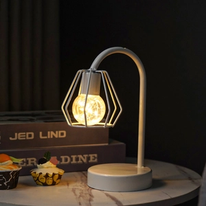 Detail of white geometric iron table lamp with warm LED string light on marble table