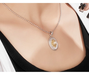 Detail view of 925 silver necklace with mother-of-pearl oval pendant and gold floral accent