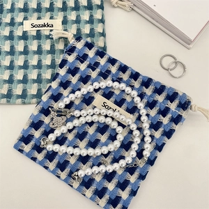 Détail de sacs à cordon tissés à carreaux et ensemble de bijoux en perles avec breloque Saturne