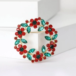Macro shot of wreath brooch with red and green rhinestones on gold metallic base