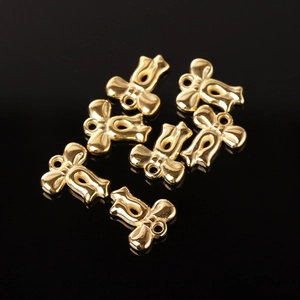Golden CCB bow-knot charms for DIY jewelry making displayed on a black background