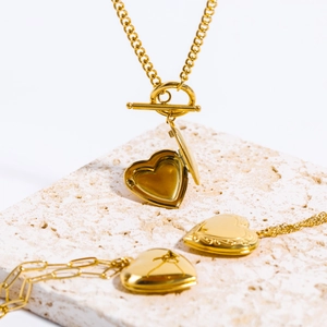 Detail showing 18k gold heart locket pendant with toggle clasp on a Cuban chain necklace