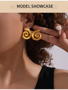 Gros plan de boucles d'oreilles dorées à double spirale portées par un mannequin