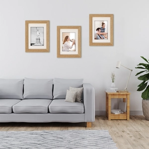 Three-piece solid wood photo frame set in light natural finish on a modern white wall
