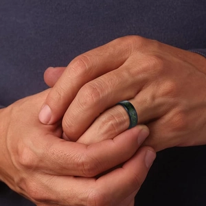 Schwarzer Herrenring aus Edelstahl mit grüner Drachen-Einlage an der Männerhand