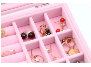 Macro detail of pink velvet jewelry box showing multiple compartments for rings and earrings