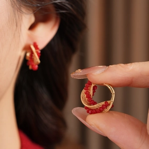 Detailed macro of vintage red beaded twisted hoop earrings with golden wire woven finish