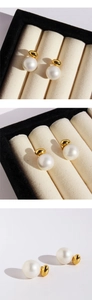 Detail showing high-luster large white pearls with minimalist gold bean-shaped accents