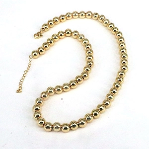Polished gold beaded necklace with adjustable lobster clasp on white background