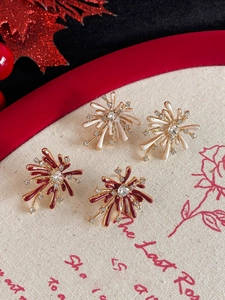 Detail of red and cream firework earrings with rhinestones on a textured canvas backdrop