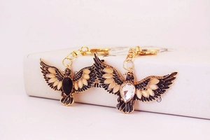Detail of eagle keychains with rhinestones and black enamel finish on white background