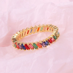 Detailed view of rainbow rectangle cut gemstones set in a golden band on pink paper