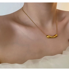 Close-up of a gold-plated irregular fluid pendant necklace on a model's collarbone
