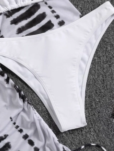 Close-up of three-piece swimsuit showing white high-cut bottoms and black ink-wash patterns