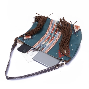 Detail of bohemian tote bag featuring ethnic patterns, brown tassels, and leather straps