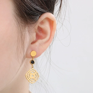 Gros plan sur boucles d'oreilles plume dorée avec gemme noire et motif mandala