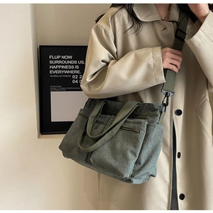 Close-up of green corduroy crossbody bag with multiple zippers and a wide shoulder strap