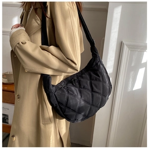 Model wearing a black quilted dumpling bag with adjustable wide strap for casual style